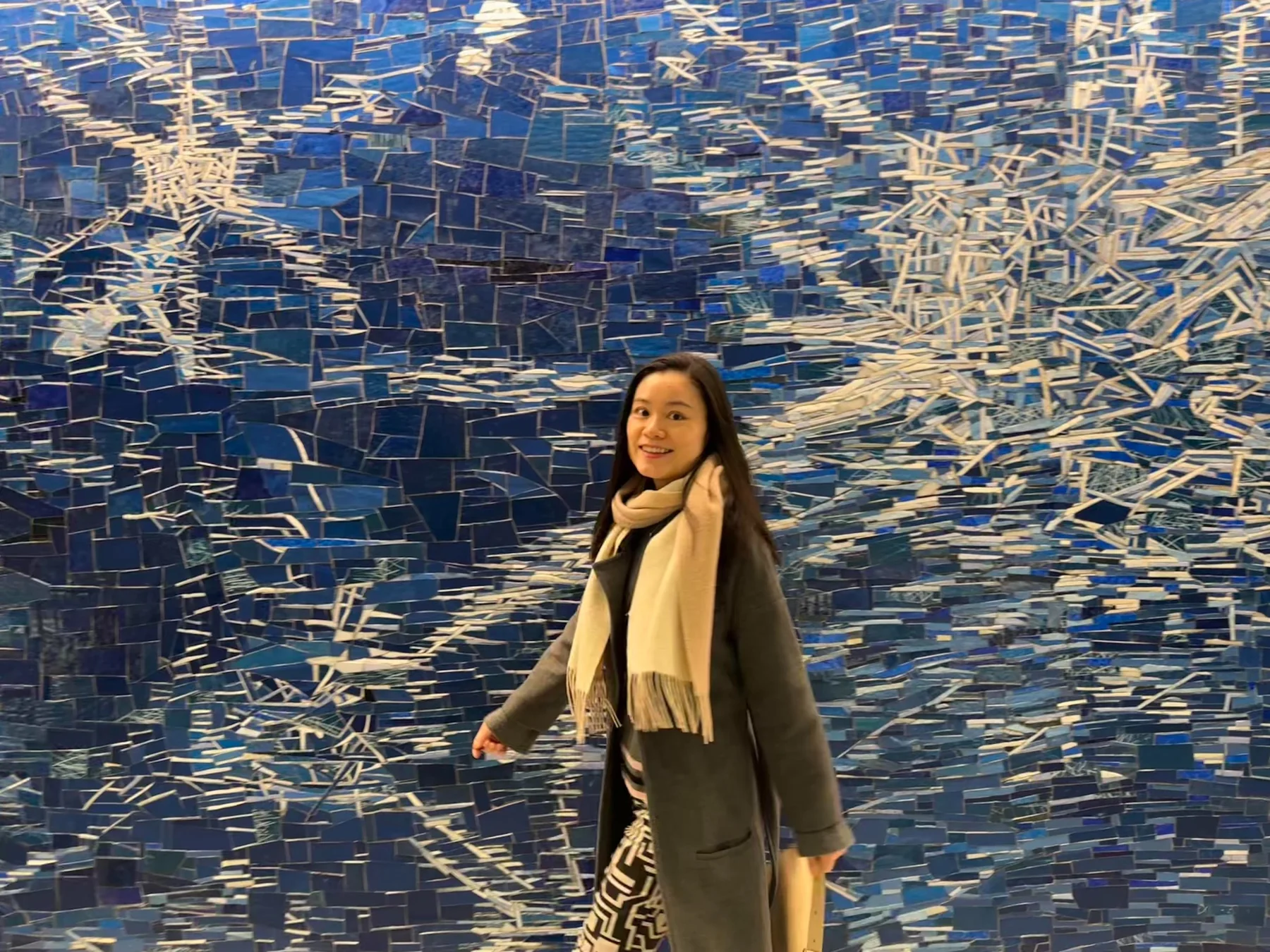 Lin smiling against a blue mosaic art wall